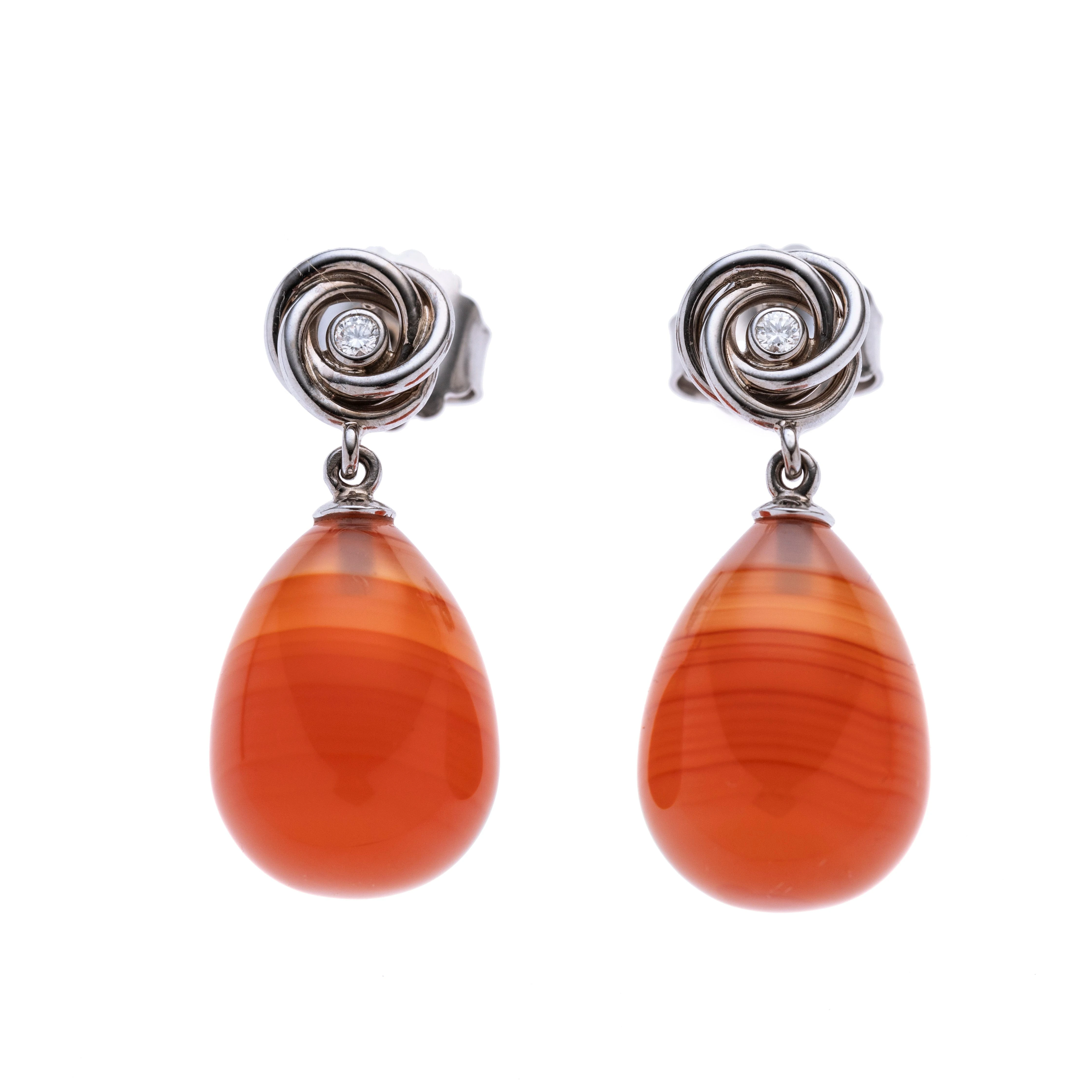 Je ein Kranz aus ineinander verschlungenen Ringen mit einem Brillanten, daran abgehängt eine orange-gestreifte Achat-Pampel.