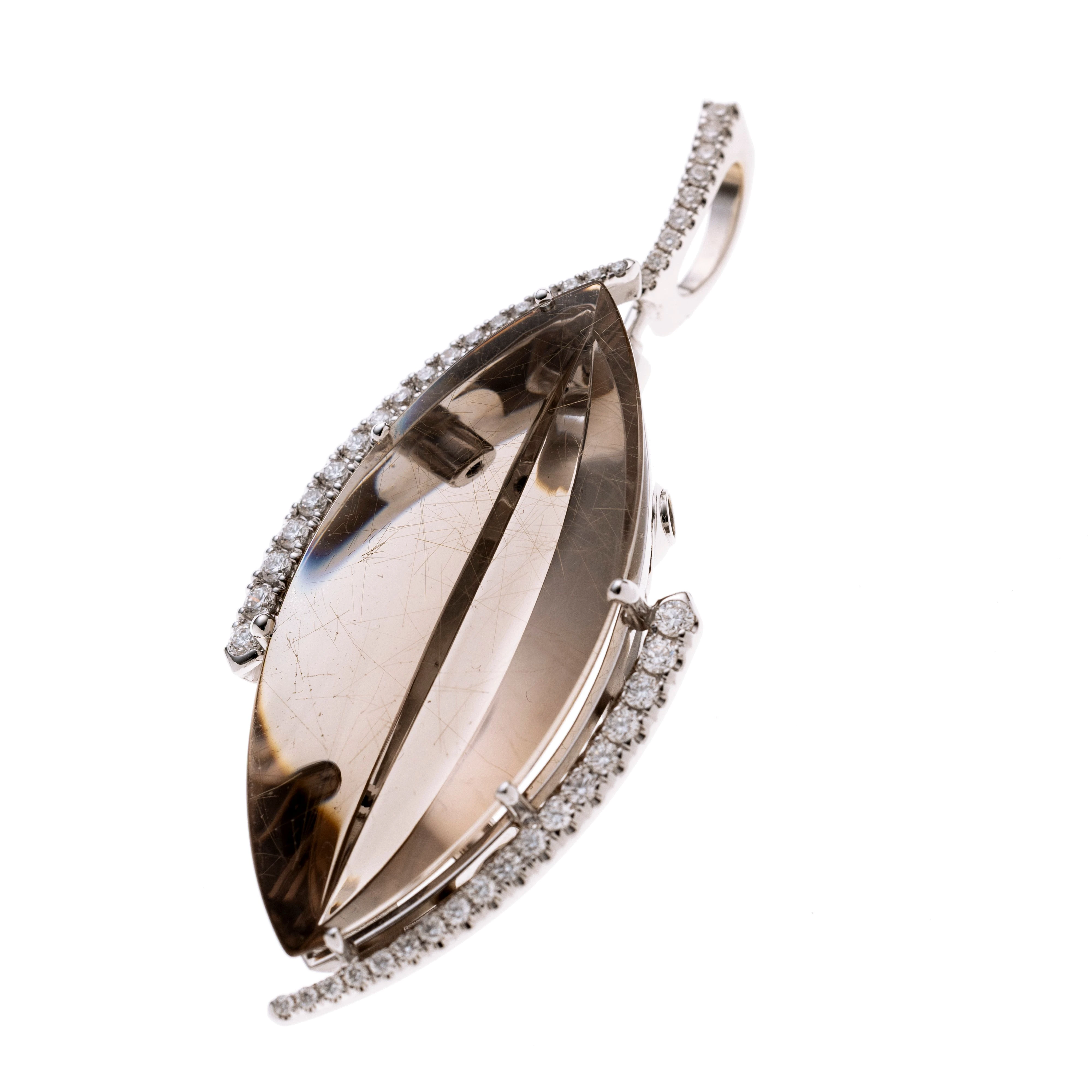 Ein navetteförmiger Rutilquarz im Fantasieschliff (nach Atelier Mundsteiner), asymmetrisch flankiert von zwei Weißgoldelementen mit Brillanten (insg. 36, zus. ca. 0.39 ct) im Verlauf. An einer leicht Bogenförmigen mit 8 Diamanten besetzten Öse (insg. ca. 0.13ct.) mit Bajonetteverschluss zum abnehmen. Der Verschluß kann an vier weiteren Positionen angebracht werden.