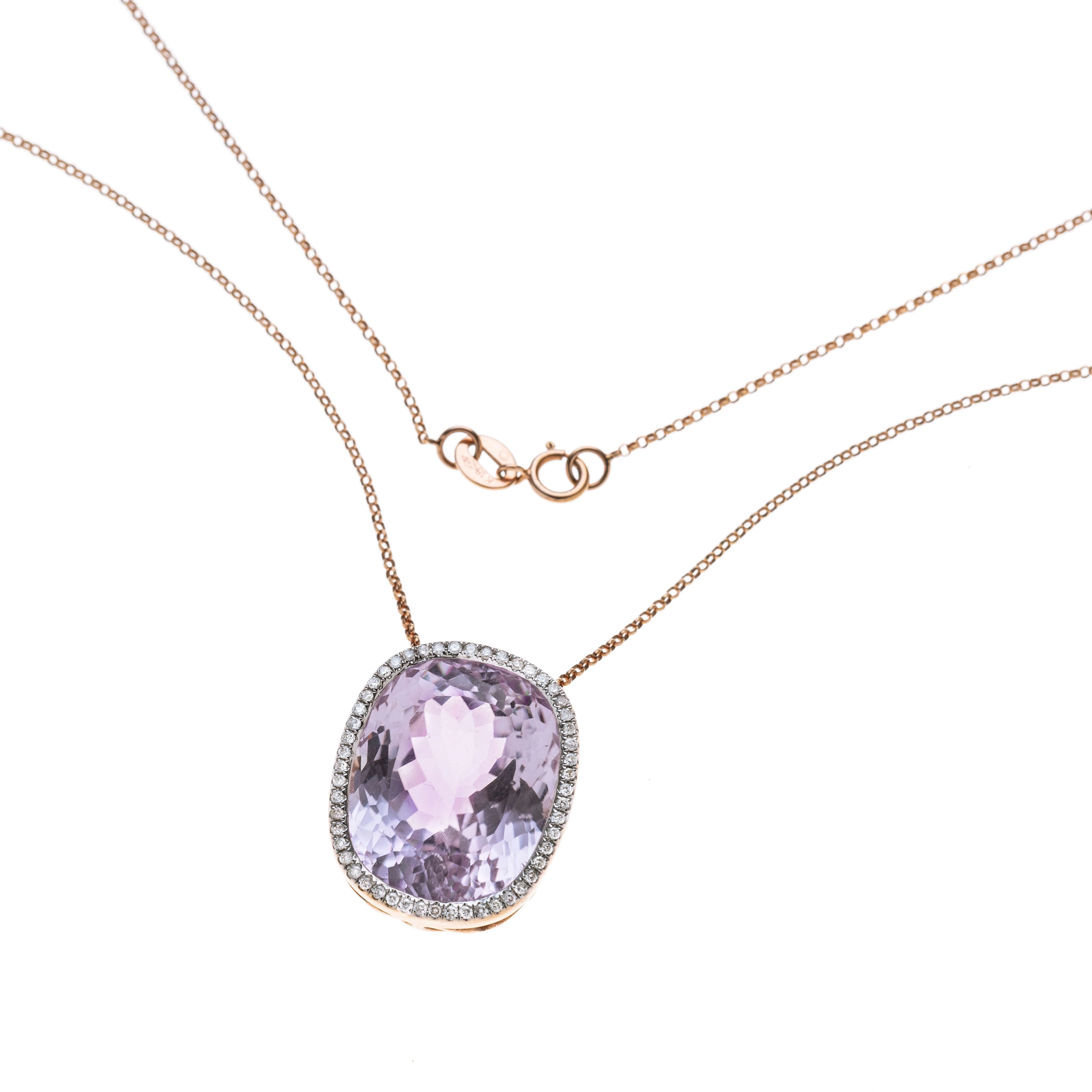 Ein Kunzit-Kissen in hoher, seitlich floral durchbrochener Zargenfassung, umgeben von 52 Diamanten in Weißgoldkrappen an zarter Ankerkette.
