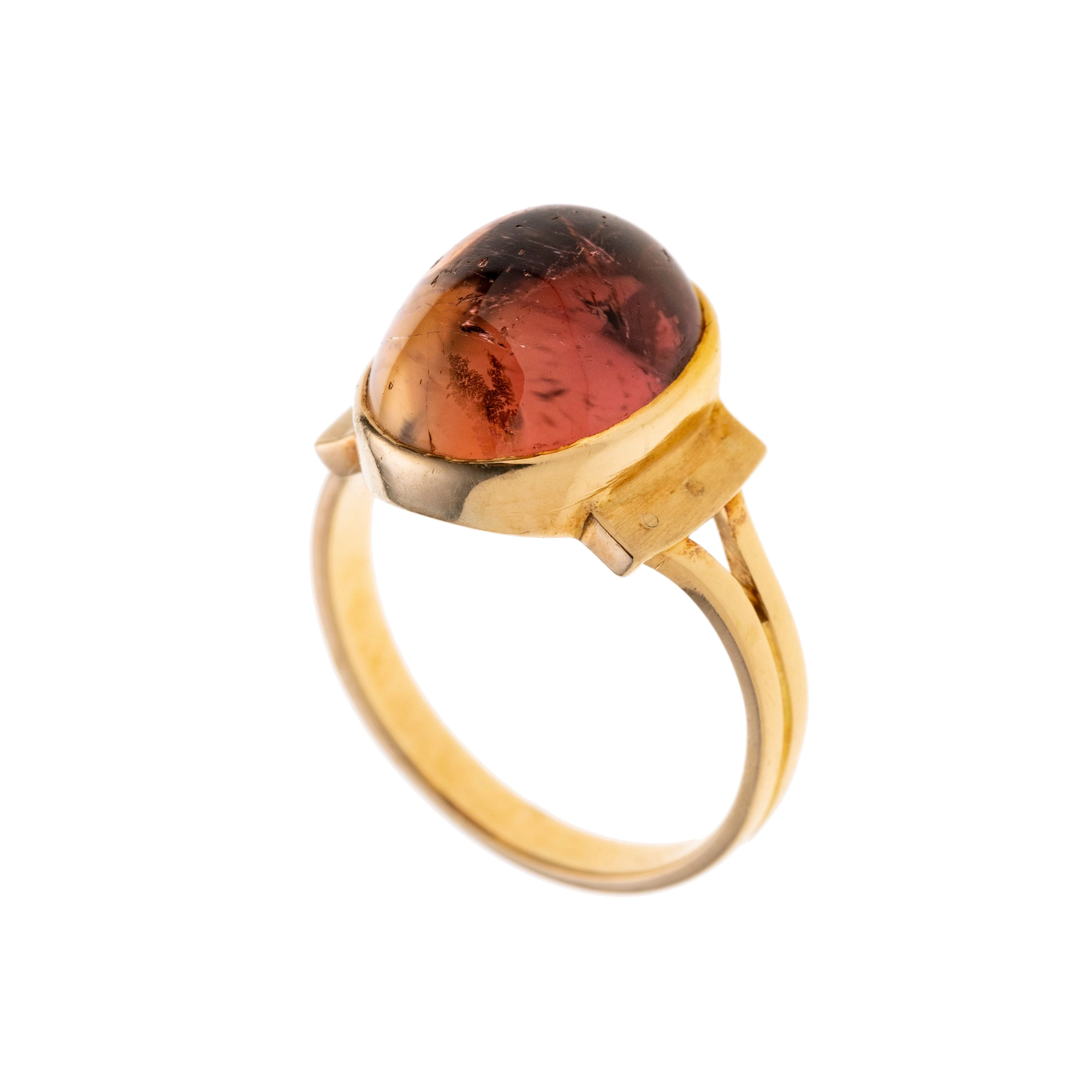 Ein pinker Turmalin-Cabochon in Zarge gefasst, leicht erhöht über den Ringschultern. Die Ringschiene ist zweigeteilt