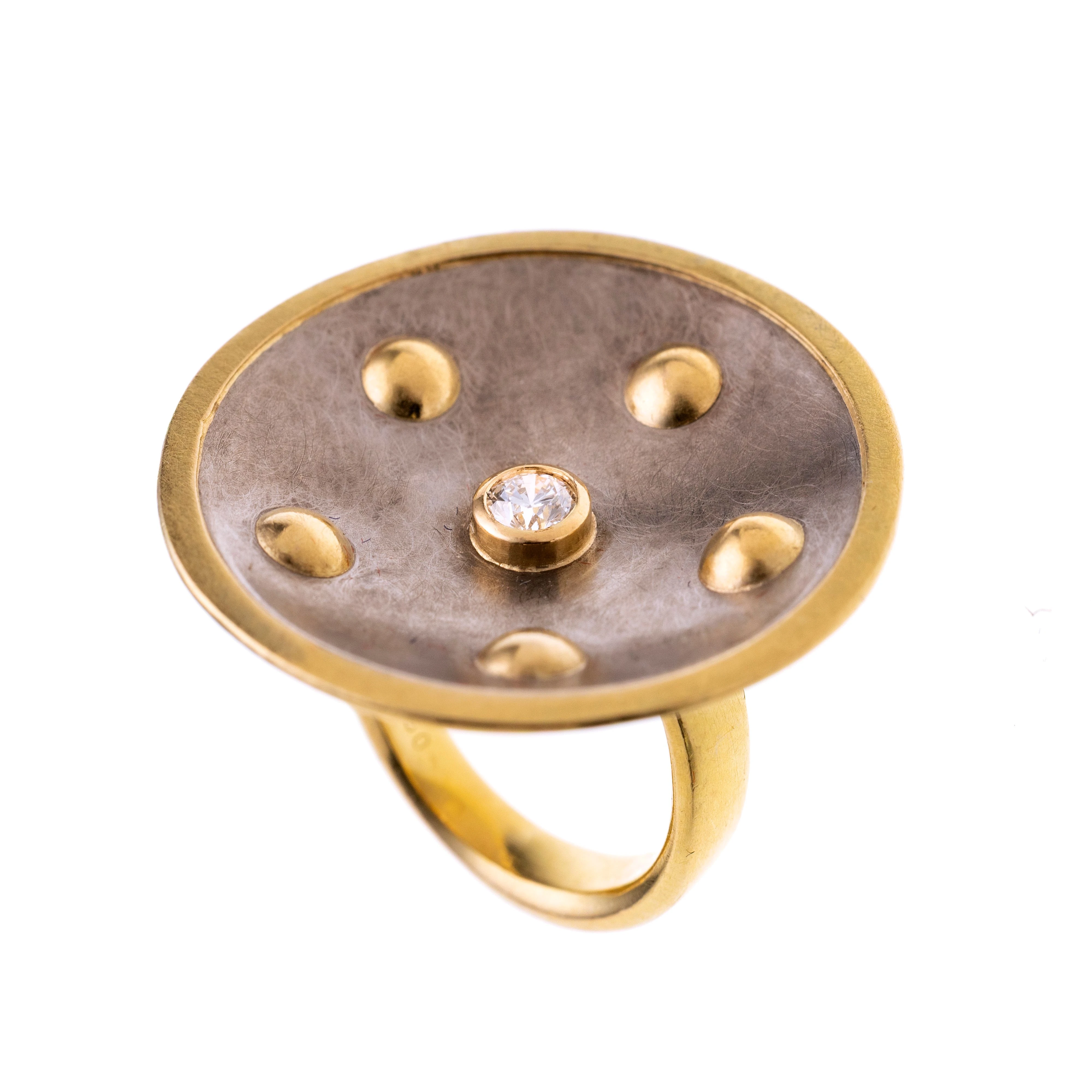 Im skulpturalen Design, gestaltet in Form einer konvex gewölbten Scheibe aus Palladium mit sechs plastisch hervorgehobenen Goldkugeln und eine, zentral ca. 0.16 ct. gesetzten Brillanten in Zargenfassung.