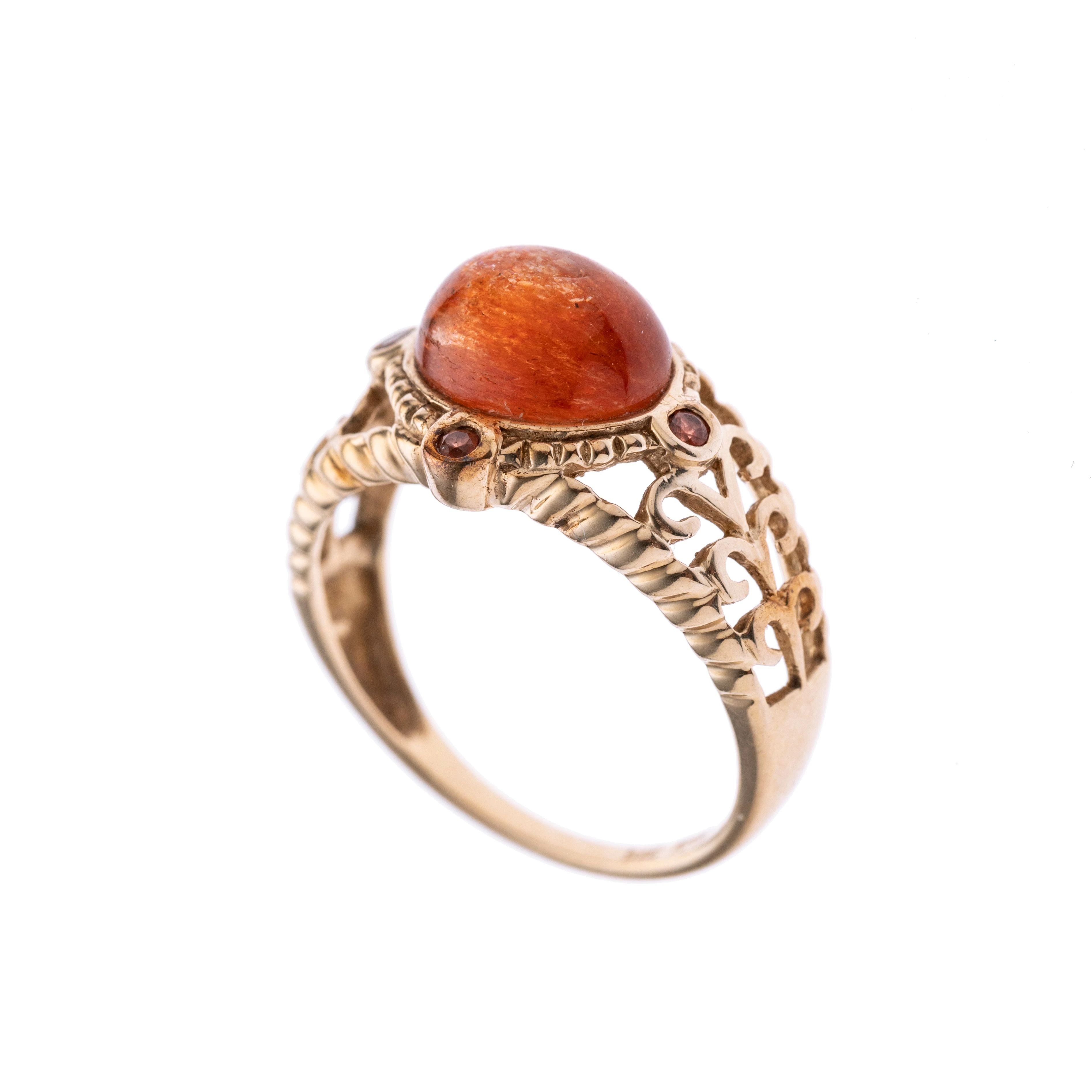 Ein feingearbeiteter goldener Ring mit geschlängeltem Muster entlang der Ringschiene. In der Mitte ein Sonnenstein, der von vier kleineren geziert wird. Signiert „MDI“.