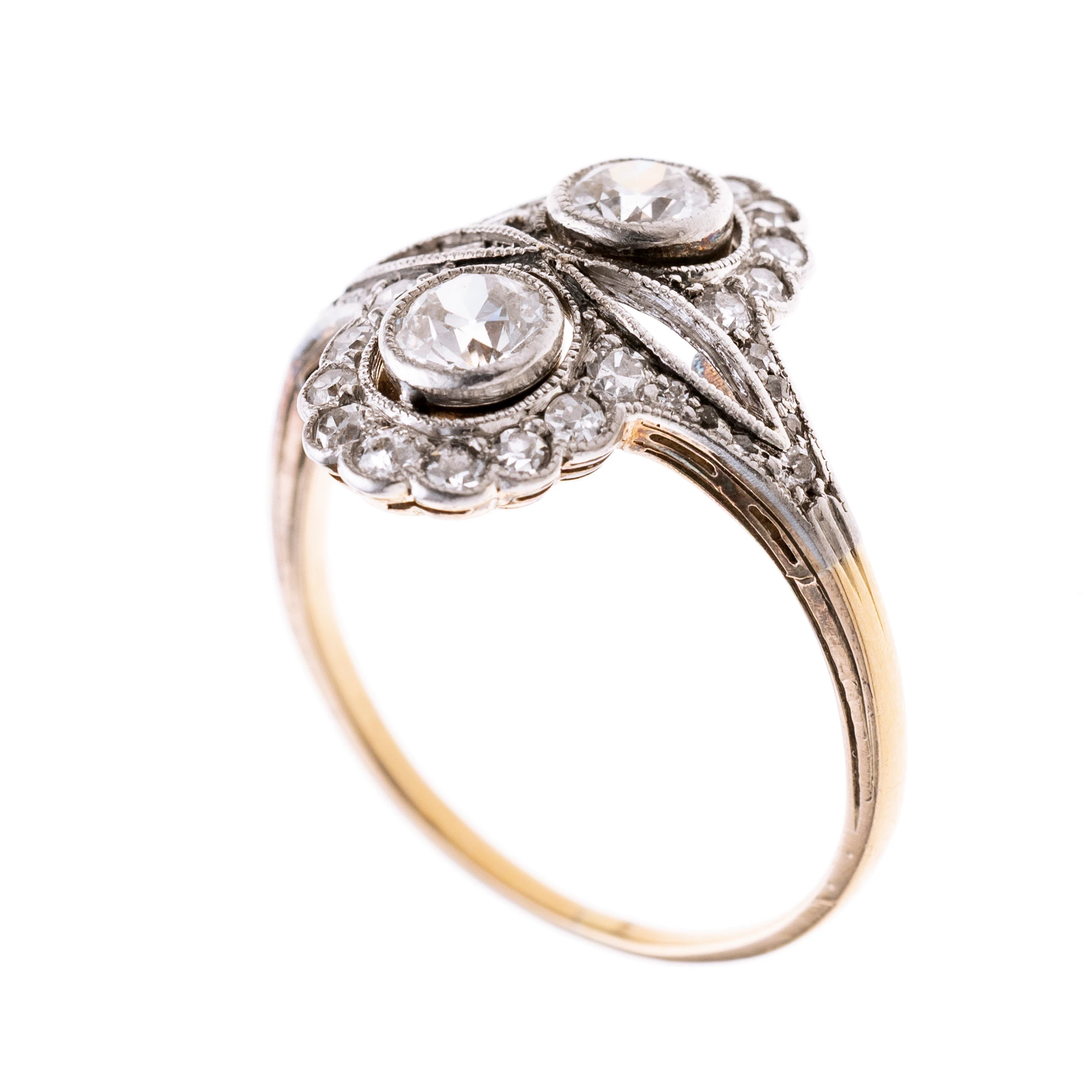 Ovaler, ájour gearbeiteter Ringkopf, platiniert mit zwei in Zargen gefassten Altschliffdiamanten je ca. 0.25 ct., die daisyartig von je 9 (insgesamt 18) Altschliffdiamanten gerahmt werden. Zusatzlich ist der Ring mit insgesamt 14 Diamanten besetzt.