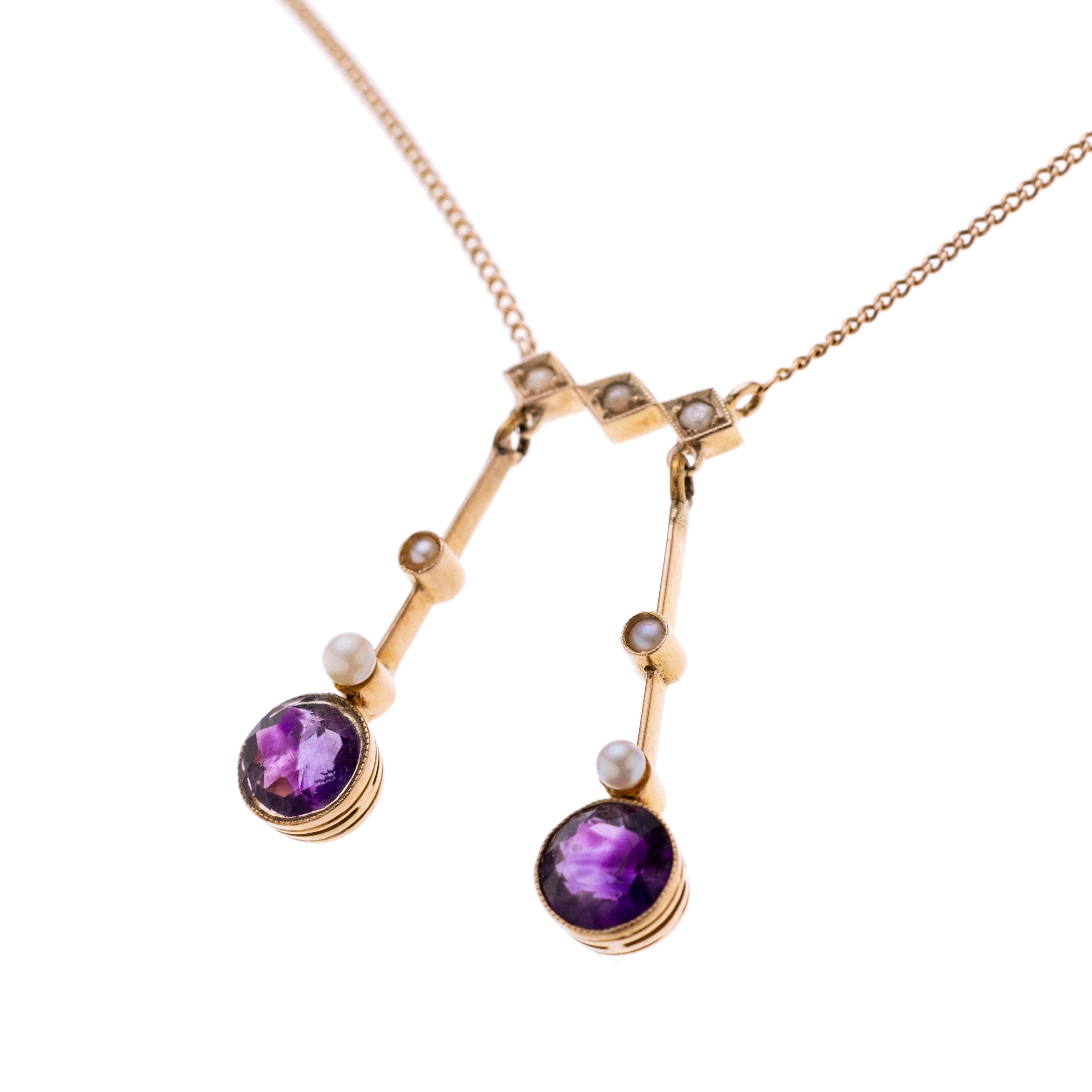 Néglige-Kette mit zwei Pendeln aus je einem Messerdraht mit zwei Perlchen und einem Amethysten als Abschluss. Unter einem Element aus drei Rauten mit je einem Perlchen, an einer Panzerkette.