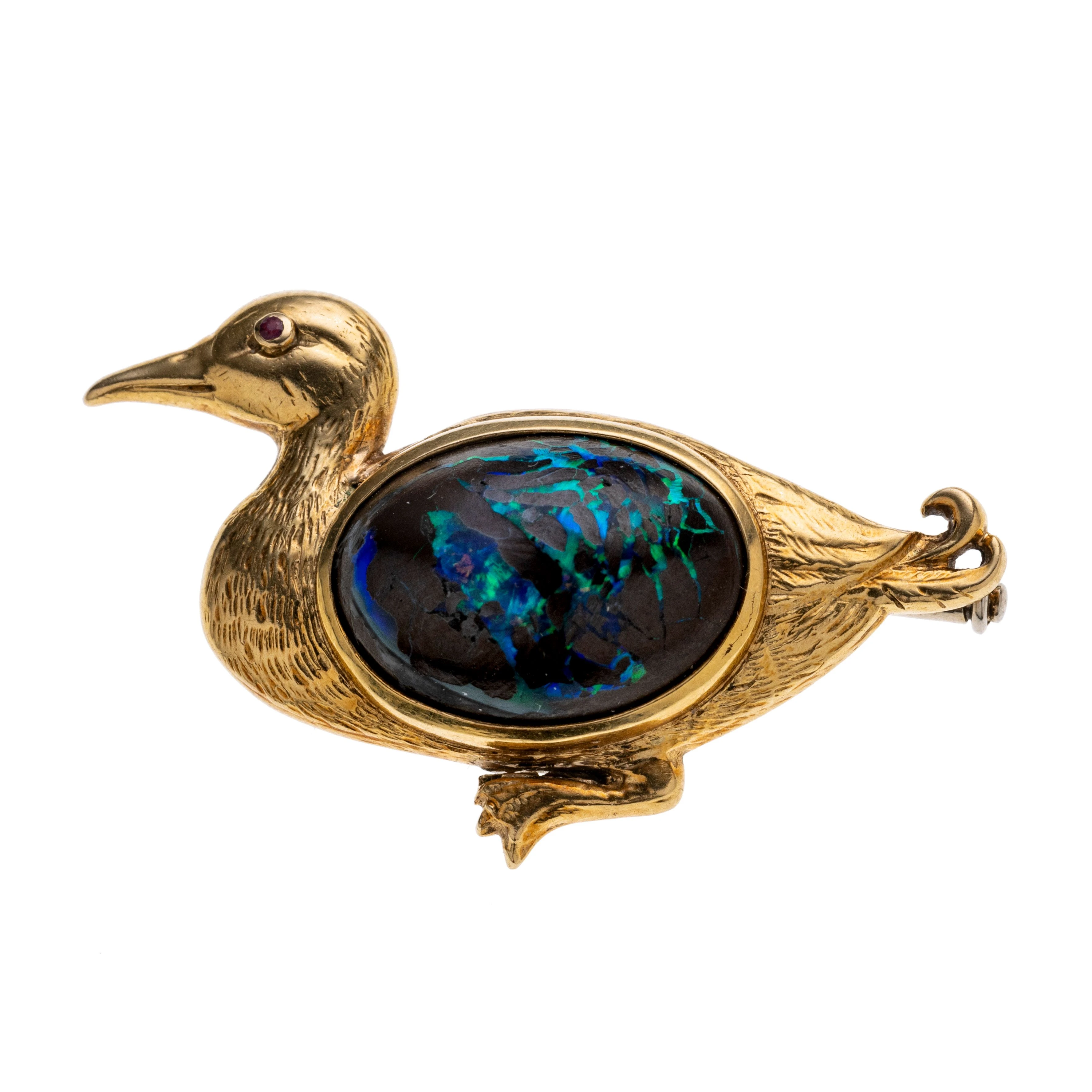 Eine Ente mit einem Rubin als Auge und einem Boulder-Opal-Cabochon im Gefieder. Broschierung aus Weißgold.