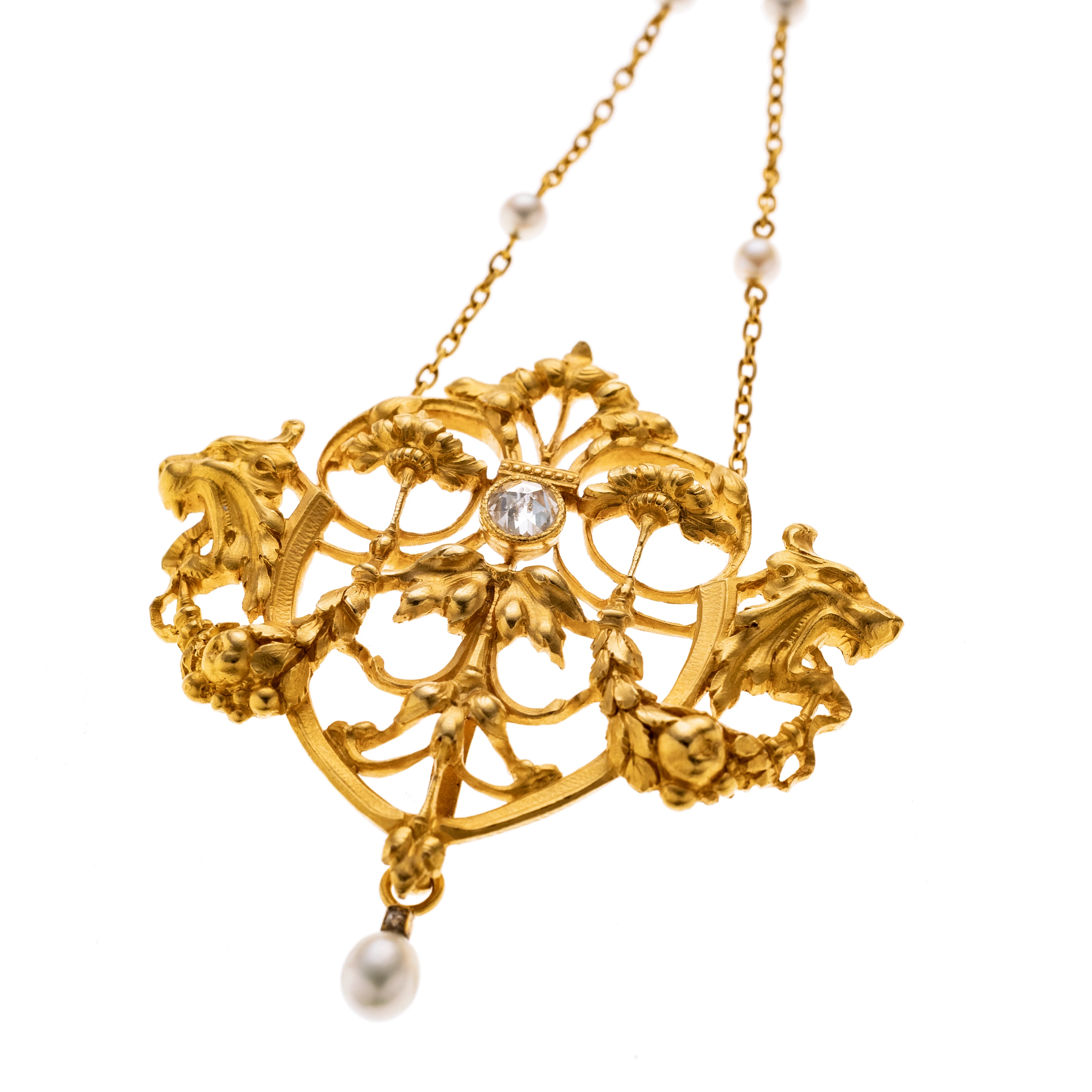 Anhänger im Stil des Jugendstil mit fast mystischer Ausstrahlung. Das ornamentale Mittelstück zeigt ein symmetrisches Arrangement aus geschwungenen, floralen und rankenartigen Elementen in opulenter. Im Zentrum ist eine Diamantrose in einer Zargenfassung gefasst. Unten schwingt eine kleine Perle. Die feine Ankerkette ist mit kleinen Zwischenperlen akzentuiert.