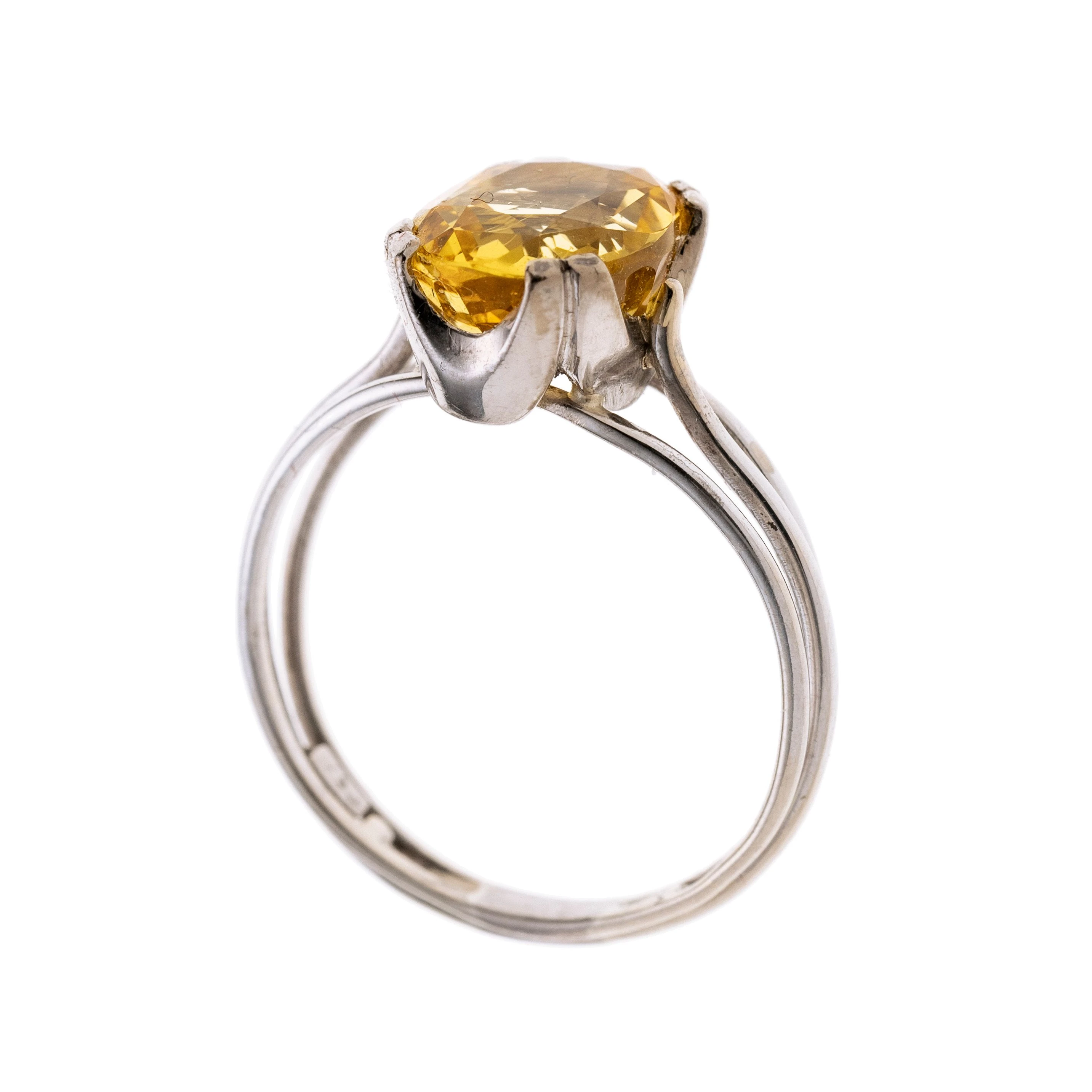 Eine dreigeteilte Ringschiene , mittig in Krappen gefasst ein gelber Saphir.