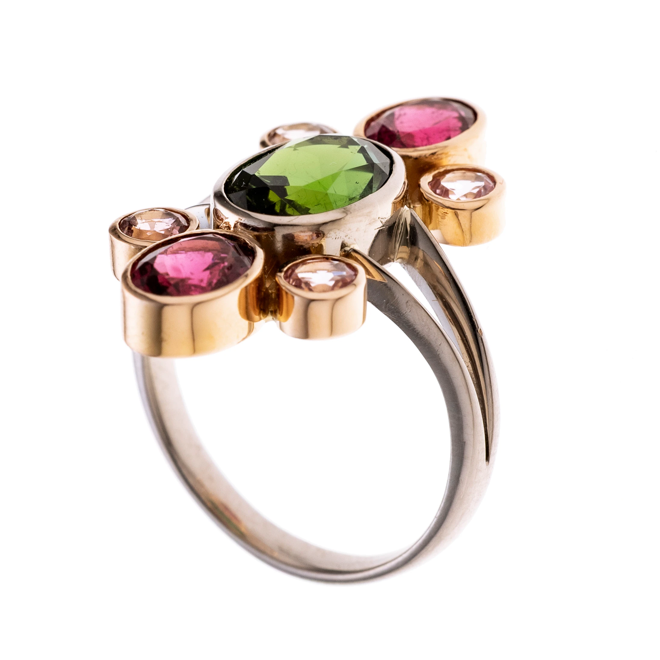 Ein grüner ca. 3 ct. Turmalin im Ovalschliff, oben und unten von je einem ovalem pinken Turmalin (je ca. 1,03 ct.) und zwei rosafarbenen Turmalinen (je ca. 0.20 ct.) flankiert. Gefasst in roségoldenen Zargen, an einer weißgoldenen Ringschiene mit gespaltenen Schultern.