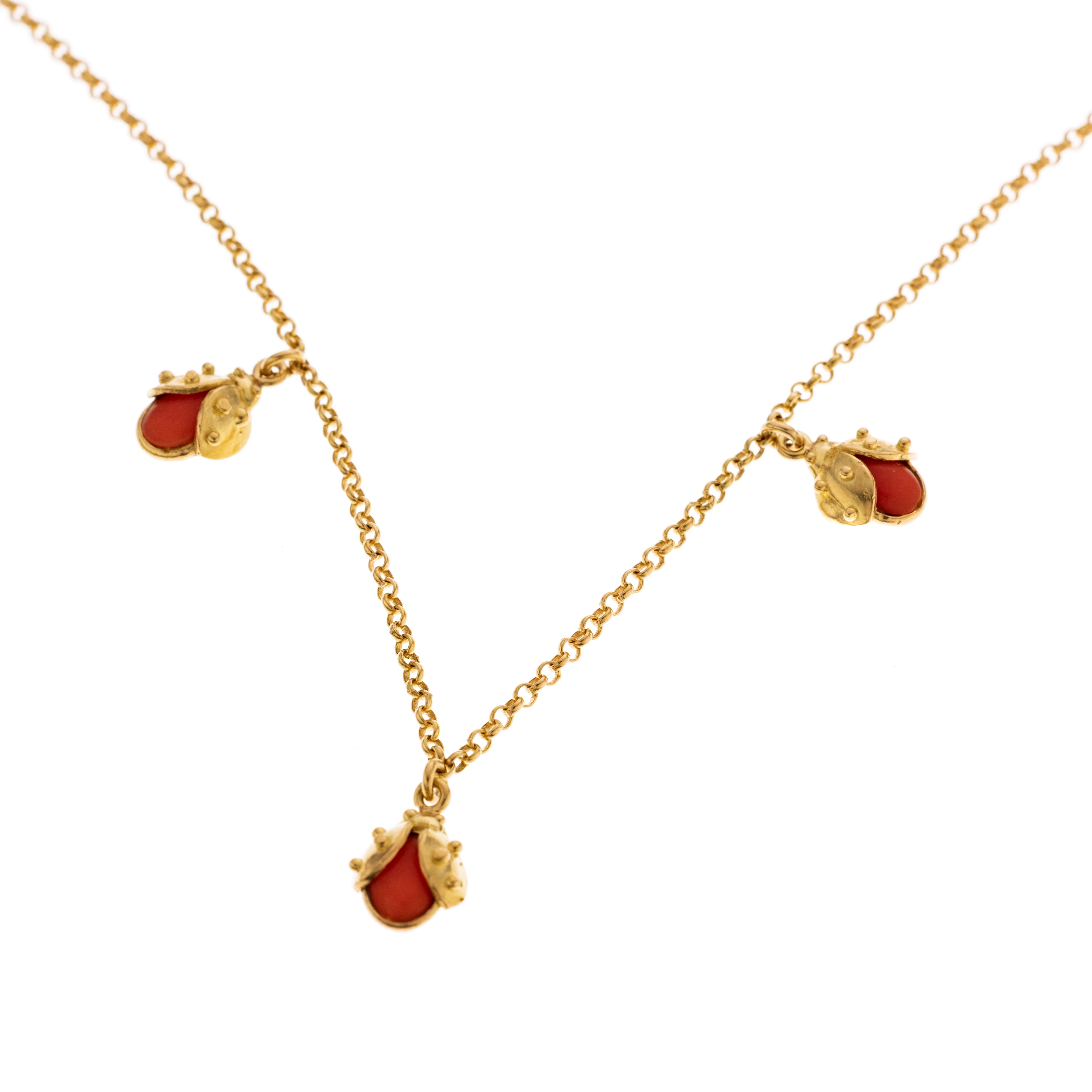 Eine Rundankerkette mit drei Marienkäfer-Anhängern, besetzt mit drei Korallen-Cabochons.