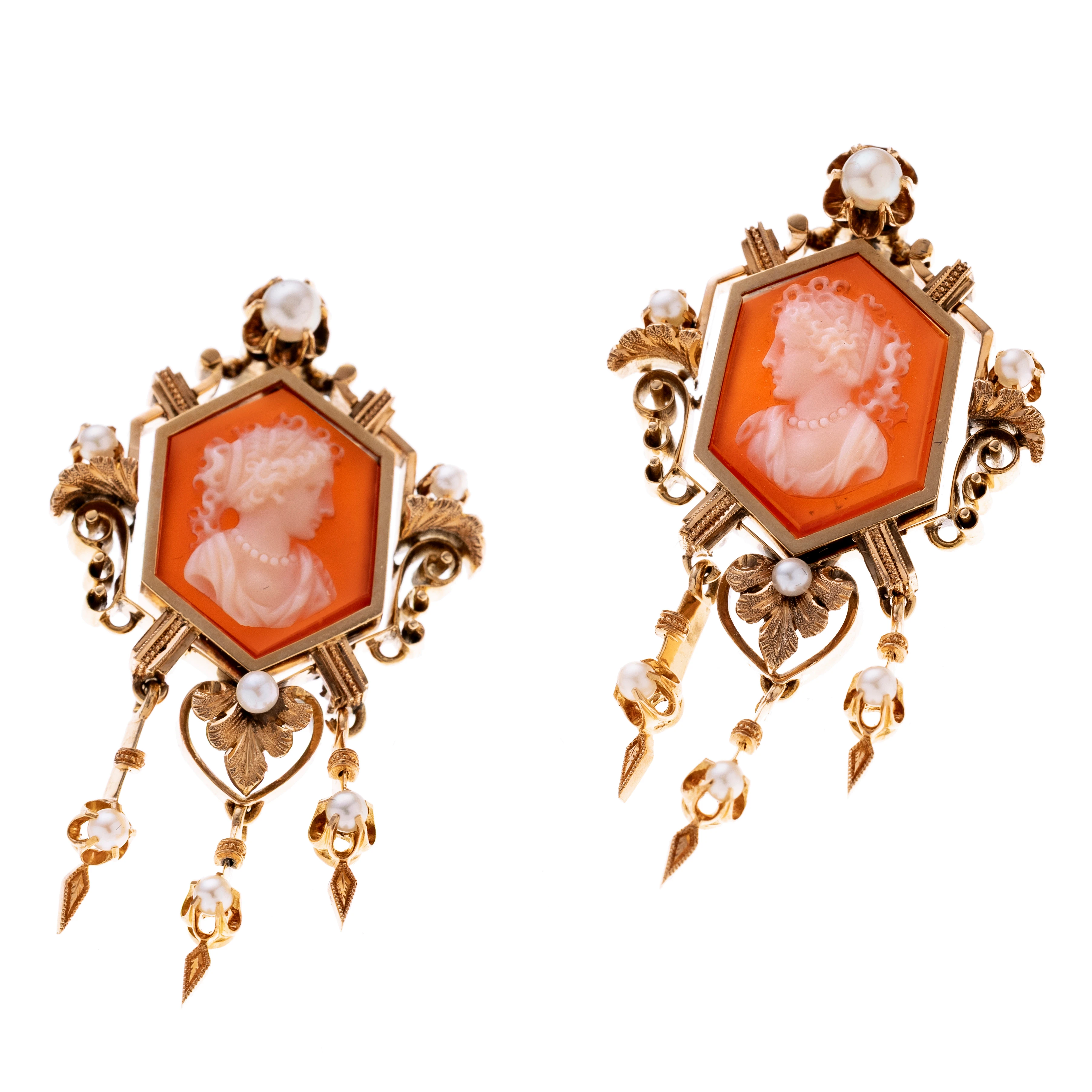 Ohrgehänge im historischen Stil. Im Zentrum je eine fein geschnittene Achatlkamee, die das nach links/ rechts blickende Profil einer Dame mit kunstvoll gelockter Frisur und Perlenschmuck zeigt. Die sechseckigen Fassungen sind ornamental gestaltet und werden von filigranen Voluten, Blütenmotiven und Saatperlen akzentuiert. Lebendigkeit verleihen je 3 Pendeloque-Elemente, die ebenfalls Perlbesetz und Verzierungen tragen.