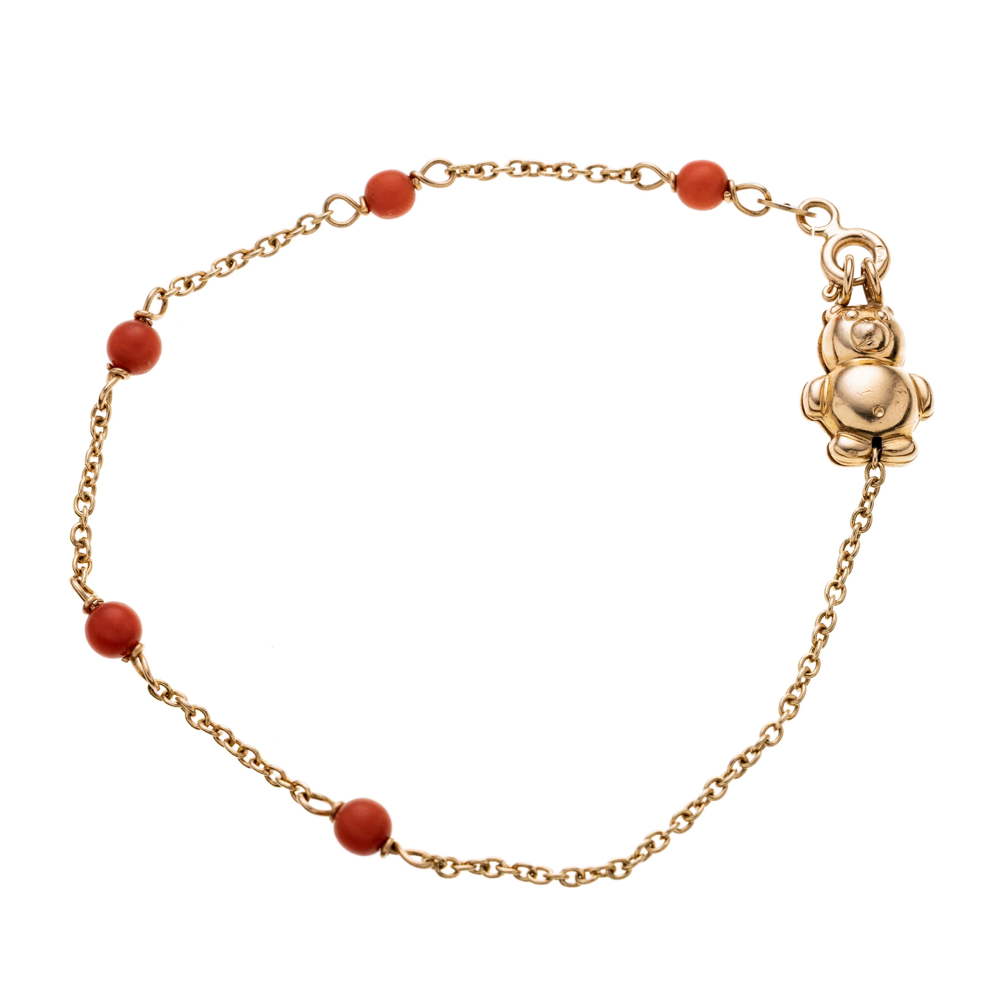 Ein feines Armband gefertigt aus 750/- Gelbgold (Ankerkette) mit 5 Korall-Kugeln in gleichen Abständen und einem kleinen Bärchen (gest. BREV.) als Verschlusselement.